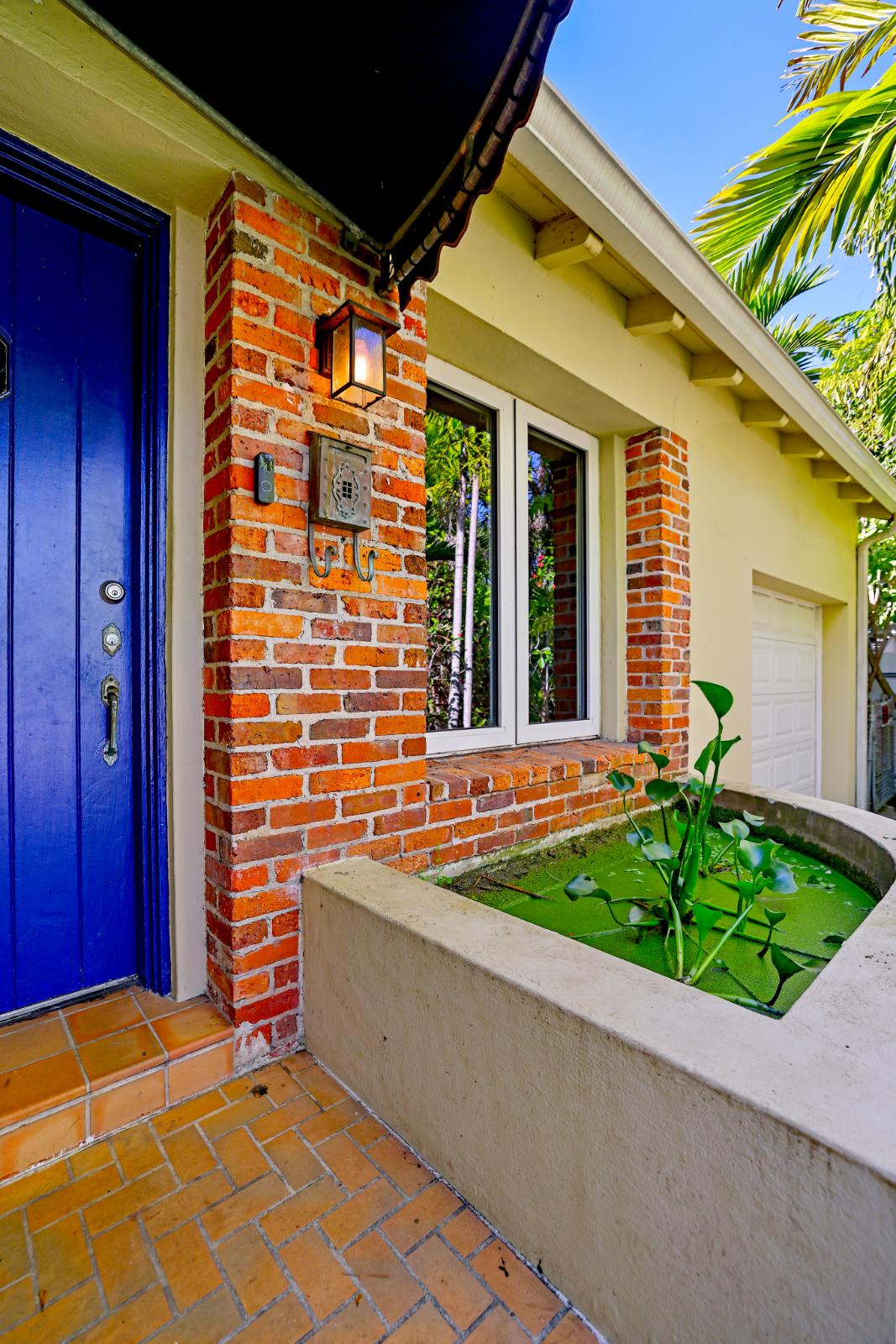 Side entry with blue door and mature tropical landscaping